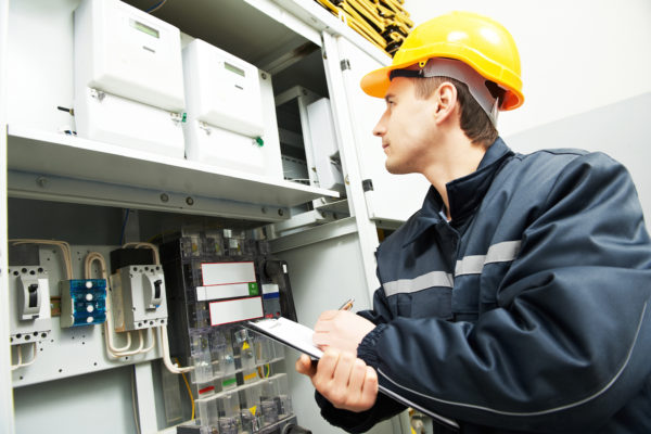 electrician builder engineer inspector checking data of equipment in fuse box